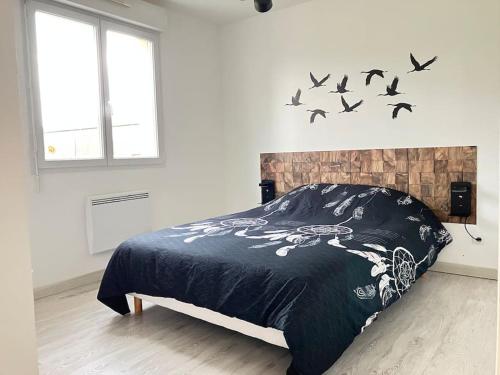 1 dormitorio con 1 cama con pájaros en la pared en Séjour bucolique au lac du der, en Giffaumont-Champaubert