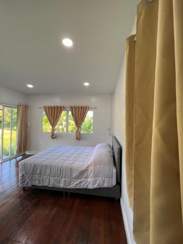 a bedroom with a bed and two windows at มานาตาฟาร์มสเตย์ in Ban Thong Noi (1)