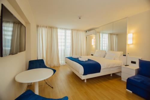 Orbi City Central Aparthotel في باتومي: غرفة نوم بسرير وطاولة وكراسي