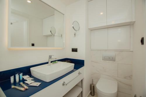 a white bathroom with a sink and a toilet at Orbi City Central Aparthotel in Batumi