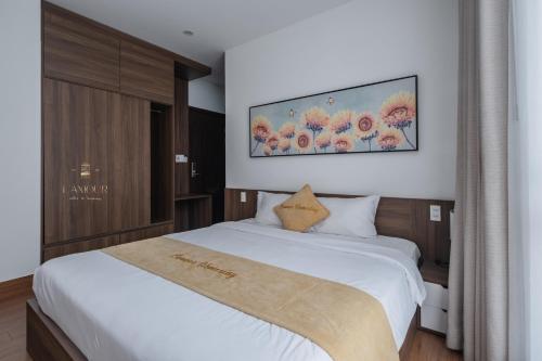a bedroom with a large white bed and a tv on the wall at Lamour homestay in Thôn Kim Long (1)