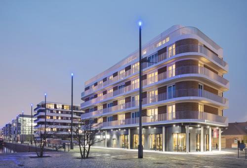 un grand bâtiment éclairé dans une ville dans l'établissement THE LIBERTY Hotel Bremerhaven BW Signature Collection, à Bremerhaven