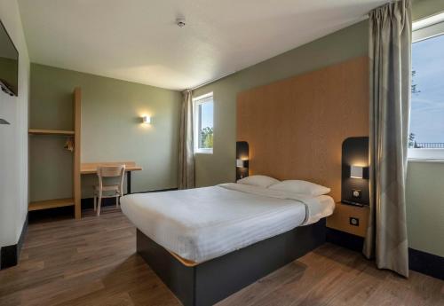 a bedroom with a large bed and a table and a window at B&B HOTEL Niort Marais Poitevin in Niort