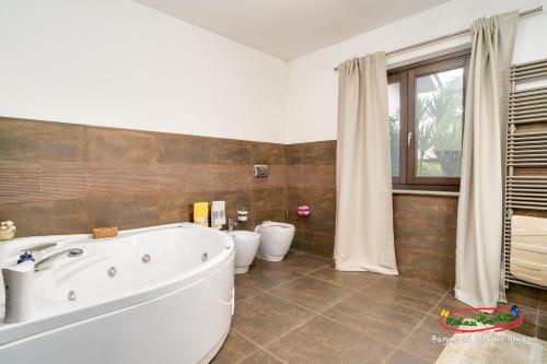 a bathroom with a tub and two toilets in it at Relax nel verde in Bracciano