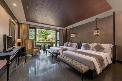 two beds in a room with a desk and a television at Hillcreek Gardens Tagaytay in Alfonso