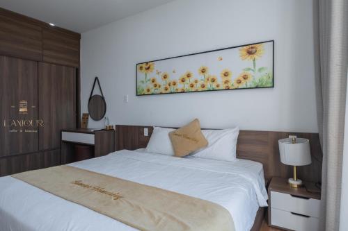 a bedroom with a white bed with a painting on the wall at Lamour homestay in Thôn Kim Long (1)