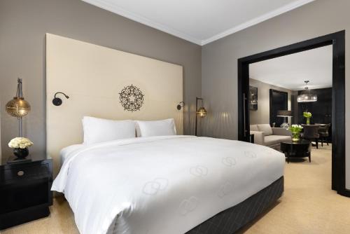 a bedroom with a large white bed and a living room at Sofitel Shahd Al Madinah in Al Madinah