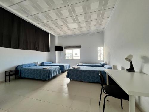 Pokój z 2 łóżkami, stołem i biurkiem w obiekcie Hostal Kaizen w mieście La Nucía