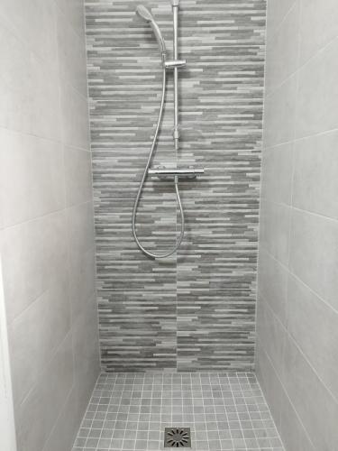 une douche dans une salle de bain avec un mur carrelé dans l'établissement Studio du Roc des Garrigues, à Langlade