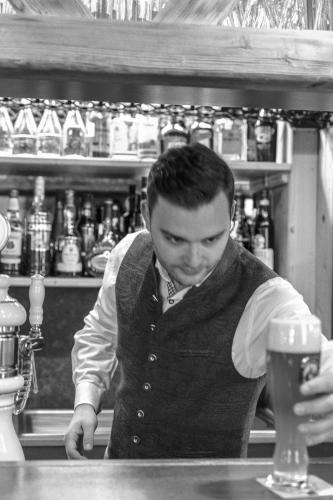 a man standing behind a bar with a glass of beer at Alpenhotel Fernau in Neustift im Stubaital