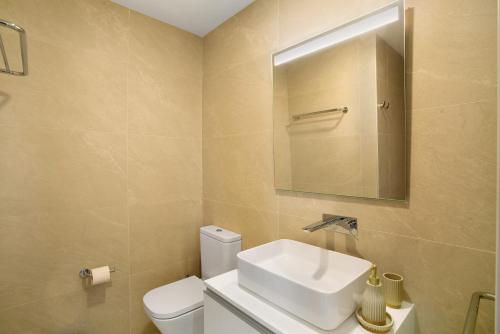 a bathroom with a sink and a toilet and a mirror at Penthouse Aliseo on the beach in Las Palmas de Gran Canaria