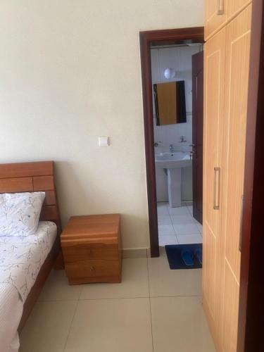 a bedroom with a bed and a bathroom with a sink at ADRIEL HOMES WOODLAND CENTEr in Kigali