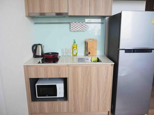 a small kitchen with a microwave and a refrigerator at Ramada素坤逸87 Loft 空中酒吧 高层景观 BTS On Nut in Bangkok