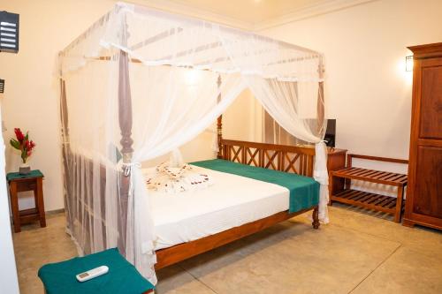 a bedroom with a bed with a canopy at New Mangosteen Garden Villa in Hikkaduwa