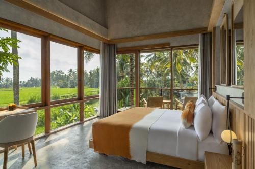 a bedroom with a bed and large windows at Inara Alas Harum in Ubud