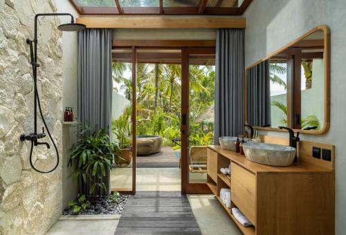a bathroom with a sink and a shower with a mirror at Inara Alas Harum in Ubud