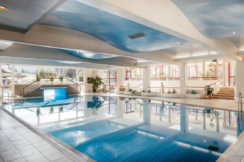 an indoor swimming pool with a blue ceiling at Thermenwelt Hotel Pulverer in Bad Kleinkirchheim