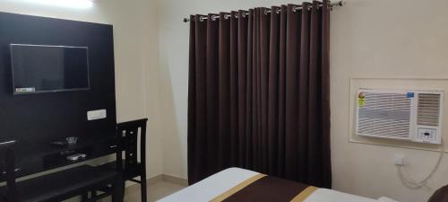 a bedroom with a black curtain and a television at J P PALACE in Kushinagar