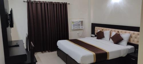 a bedroom with a large bed with brown curtains at J P PALACE in Kushinagar