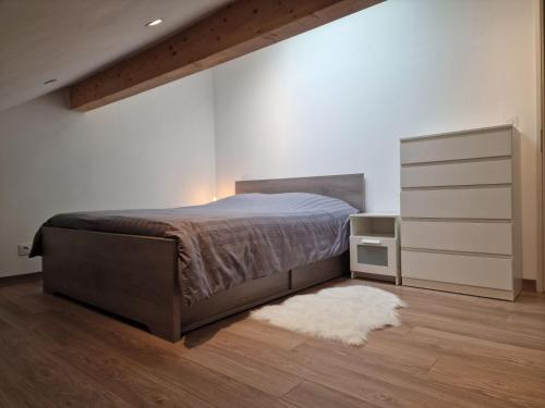 una camera con letto, cassettiera e tappeto di Appartement rez de jardin a Saint-Martin-dʼUriage