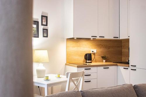 cocina con armarios blancos, mesa y sofá en Przytulne mieszkanie w Centrum en Varsovia