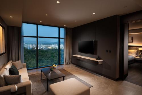 a living room with a couch and a tv at DoubleTree By Hilton Seoul Pangyo Residences in Seongnam