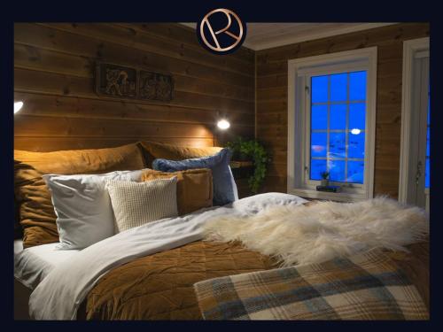 a bedroom with a large bed with a blanket and a window at Hemsen in Grøndalen