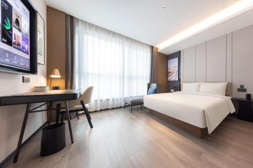 済南市にあるAtour Hotel Jinan Shungeng Covention and Exhibition Center Bayi Overpassのベッドとデスクが備わるホテルルームです。