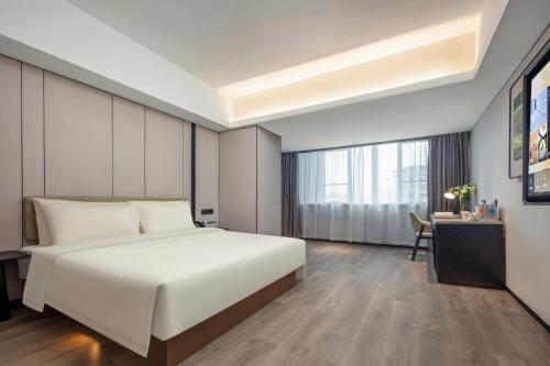 a bedroom with a large white bed and a desk at Atour X Hotel Xiamen SM Plaza District Government in Xiamen