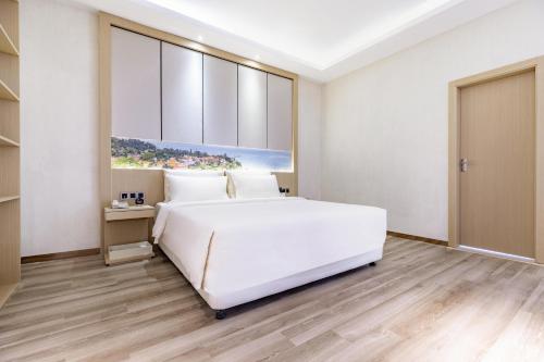 a bedroom with a large white bed and wooden floors at Atour Hotel Xiamen Xiagu Cruise Center in Xiamen