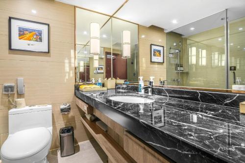 een badkamer met een wastafel, een toilet en een spiegel bij Atour Hotel Chengdu Taikoo Li Riverside in Chengdu
