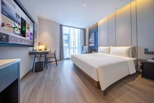 a hotel room with a large white bed and a desk at Atour Hotel Beijing Capital Airport New International Exhibition Center in Beijing