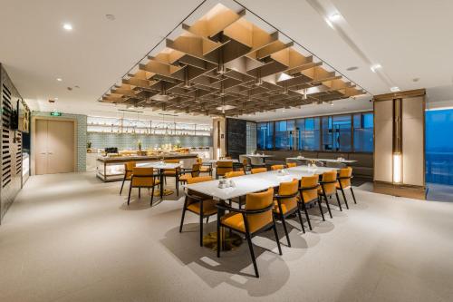 a restaurant with tables and chairs and a bar at Atour Hotel Handan New Century in Handan