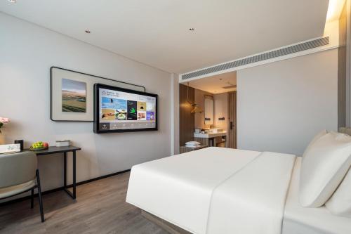 a bedroom with a white bed and a television on the wall at Atour Hotel Anji Longshan in Anji