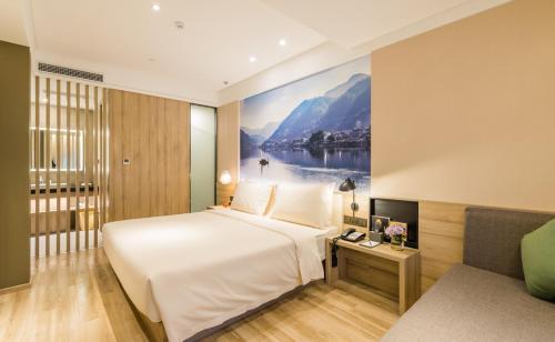 a bedroom with a large bed with a painting on the wall at Atour Hotel Hangzhou West Lake Cultural Plaza Shangtang Road in Hangzhou