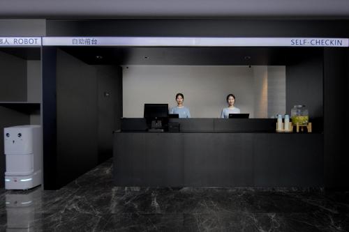 two people standing at a counter in an office at Atour Light Hotel Changsha IFC Huangxing Road Pedestrian Street in Changsha