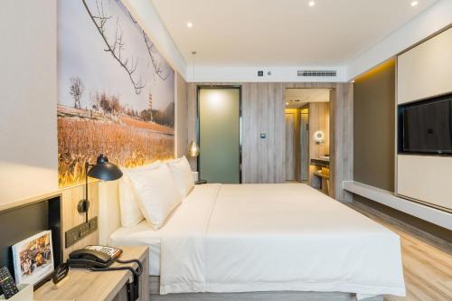 a bedroom with a large bed and a television at Atour Hotel Xuzhou East Jianguo Road Suning Plaza in Xuzhou