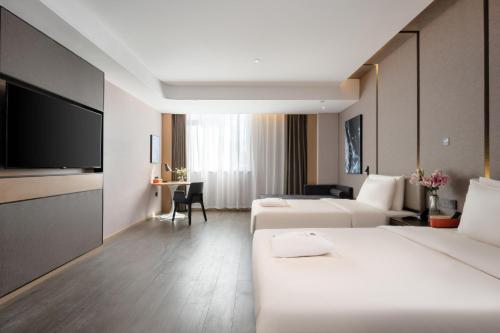 a hotel room with two beds and a flat screen tv at Atour Hotel Lijiang Old Town Waterwheel in Lijiang