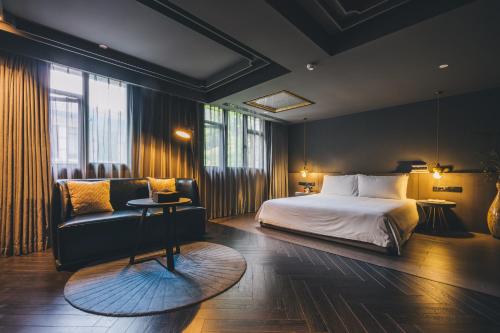 een slaapkamer met een bed, een bank en een stoel bij The Drama in Shanghai