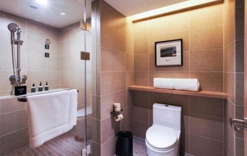 uma casa de banho com um WC e uma cabina de duche em vidro. em Atour Hotel Harbin Haxi High Speed Railway Station em Harbin