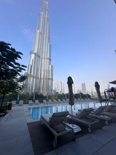 a pool with lounge chairs and two tall buildings at Luxury 3-bedroom apartment with a stunning view of the Burj Khalifa and the Fountain in Dubai