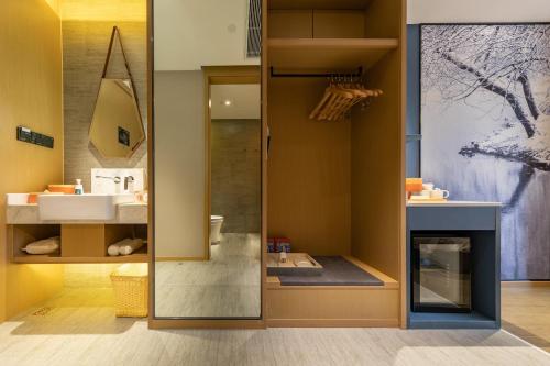 ein Badezimmer mit einem Spiegel und einem Waschbecken in der Unterkunft Atour Hotel Kunming Cuihu in Kunming