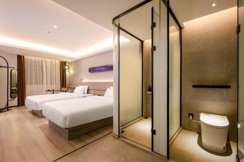 a hotel room with two beds and a mirror at Atour X Hotel Chaozhou Xiangqiao International Financial Business Center in Chaozhou