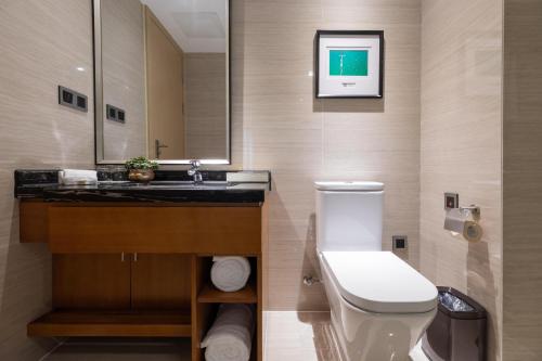a bathroom with a sink and a toilet and a mirror at Atour Hotel Xiamen Xiagu Cruise Center in Xiamen