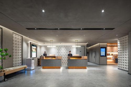 a lobby with two people sitting at a counter at Atour Hotel Anji Longshan in Anji