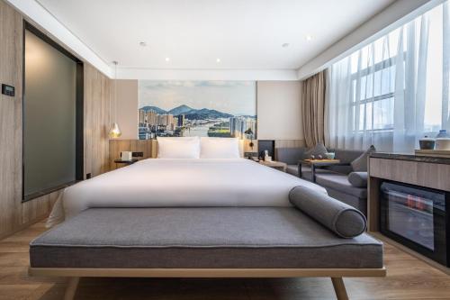 a bedroom with a large bed and a living room at Atour Hotel Zhongshan Er Road Lihe Plaza in Zhongshan