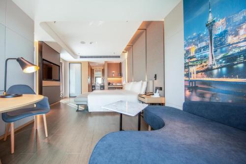 a hotel room with a bed and a desk and a couch at Atour S Hotel Zhuhai Gongbei Port NetEase Selected in Zhuhai