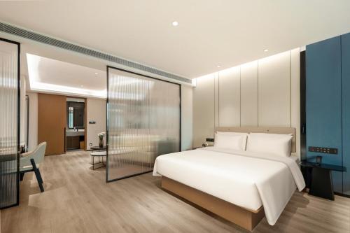 a bedroom with a large white bed and a desk at Atour Hotel Quanzhou Jinjiang Sunshine Plaza in Jinjiang