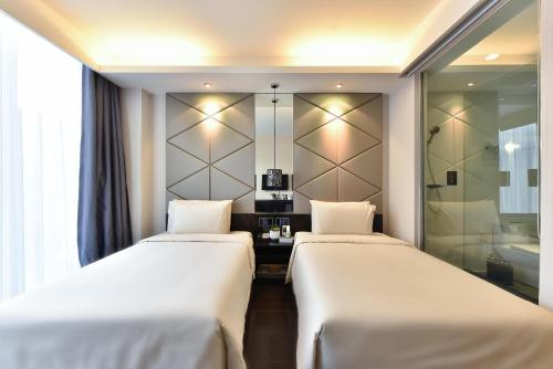 two beds in a hotel room with a bathroom at Atour Hotel Beijing Yizhuang West Rongjing Street in Daxing