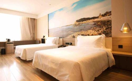 a hotel room with two beds and a painting on the wall at Atour Hotel Yantai South Station Yingchun Street in Yantai